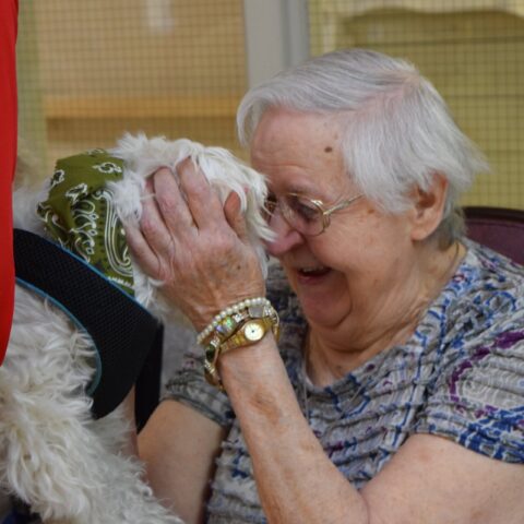 Elderly resident enjoying a visit from a dog, during the Healing Power of Pets event